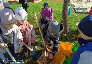 dzieci wsypują liście na taczkę