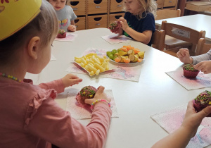 poczęstunek urodzinowy- dzieci jedzą owoce i zdrowe babeczki