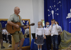 Pan Marcin przygrywa dzieciom na gitarze