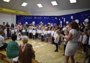 Rodzice i dzieci śpiewają piosenkę dla wszystkich pracowników przedszkola