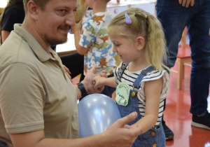 Dziewczynka z tatą podzas zabawy balonem