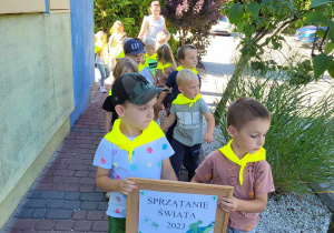 chłopcy trzymają tablicę z napisem Sprzątanie świata