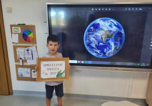chłopiec stoi przy ekranie na tle planety Ziemi