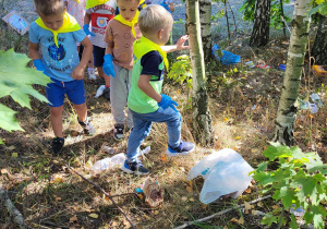 dzieci szukają śmieci po lesie