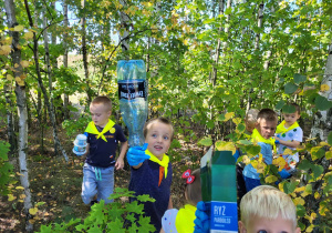 chłopcy pokazują znalezione w lesie śmieci