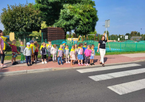 dzieci stoją z panią na chodniku
