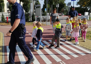 przedszkolaki przechodzą przez pasy z policjantem
