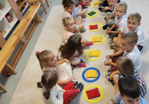 dzieci siedzą na dywanie z woreczkami