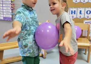 dziewczynka z chłopcem tańczą z balonem