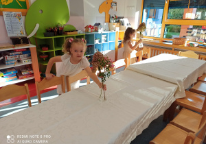 dziewczynka stawia wazon na stole