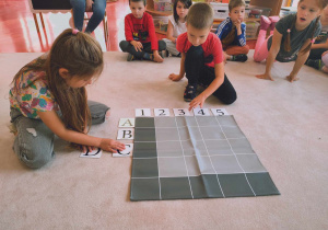 dzieci układaja cyfry i litery na macie