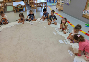 dzieci siedz ana dywanikach z ułożonymi z liter swoimi imionami