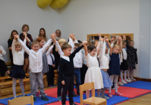 dzieci z grupy sześciolatków trzymają ręce w górze