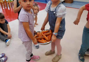 Dziewczynki niosą do mycia marchewki