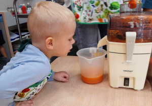 Chłopiec obserwuje wylatujący z maszyny sok