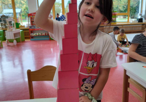 dziecko układa różowa wieżę