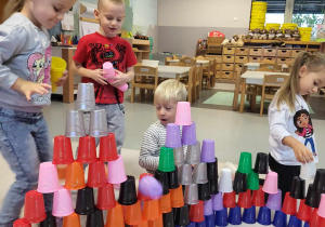 dzieci wspólnie układają wieże z kubeczków