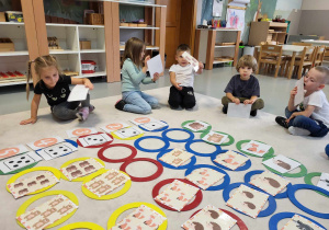 dzieci siedzą na dywanie z ilustracjami zwierząt