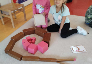 dziewczynki układą brązowe schody i różową wieżę