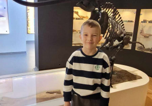 chłopiec stoi przed szkieletem mamuta