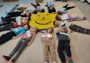 dzieci leża na plecach układając z siebie promyki słoneczka