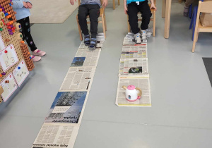 chłopcy wciągają gazety za pomocą stóp