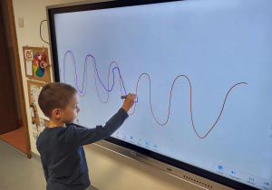 chłopiec rysuje pisakiem po śladzie na ekranie monitoru