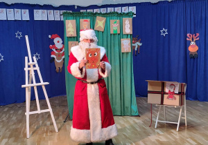 Mikołaj pokazuje dzieciom świąteczny obrazek