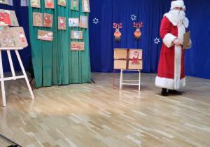 Mikołaj prezentuję galerię namalowanych przez dzieci obrazków z motywem świątecznym