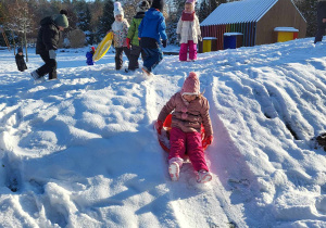 dziewczynka zjeżdża z górki ze śniegiem