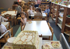 dzieci siedzą przy stolikach i czekają na tort