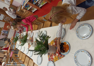 dziewczynki ustawiają na stole owoce