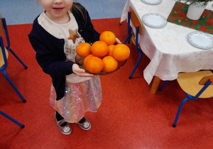 Dziewczynka niesie na stół mandarynki