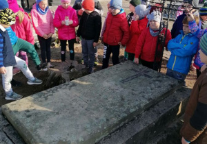 Dzieci stoja przy grobie nauczycielki 