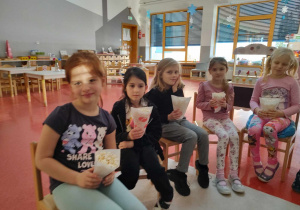dzieci siedzą trzymając popcorn