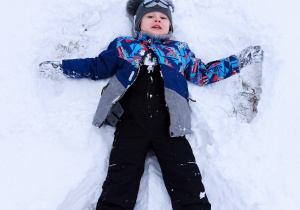 chłopiec robi aniołka na śniegu