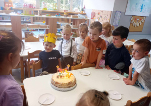 grupa dzieci stoi przy Maksymilianie wokół tortu