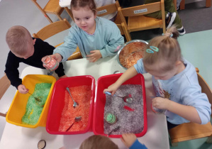 dzieci wsypują kolorową sól do słoiczków