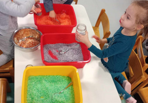 przedszkolaki wsypują kolorową sól do słoiczków