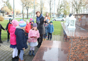 Dzieci składaja znicze pod pomnikiem 1