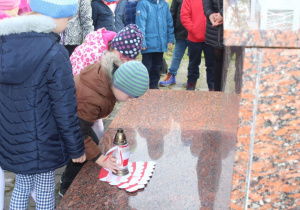 Dzieci składaja znicze pod pomnikiem 2