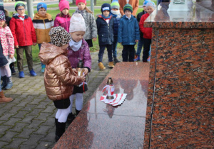 Dzieci składaja znicze pod pomnikiem 3