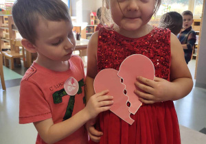 chłopiec i dziewczynka pokazują złączone połówki serca