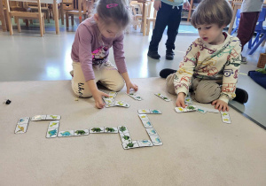chłopiec z dziewczynką grają w dinozaurowe domino