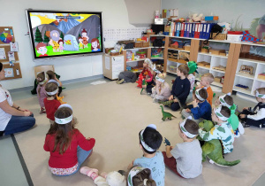 dzieci oglądają film edukacyjny o dinozaurach