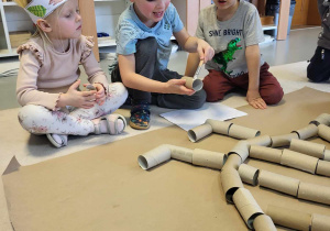 dzieci budują z rolek szkielet dinozaura