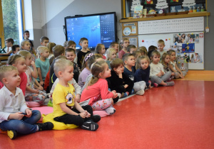 dzieci siedzą i słuchają granej muzyki