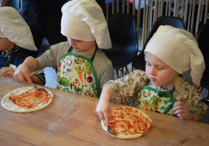 dzieci smarują pizzę sosem