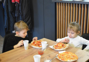 dzieci jedzą pizzzę