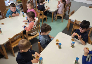 przedszkolaki siedzą przy stoliku podczas poczęstunku